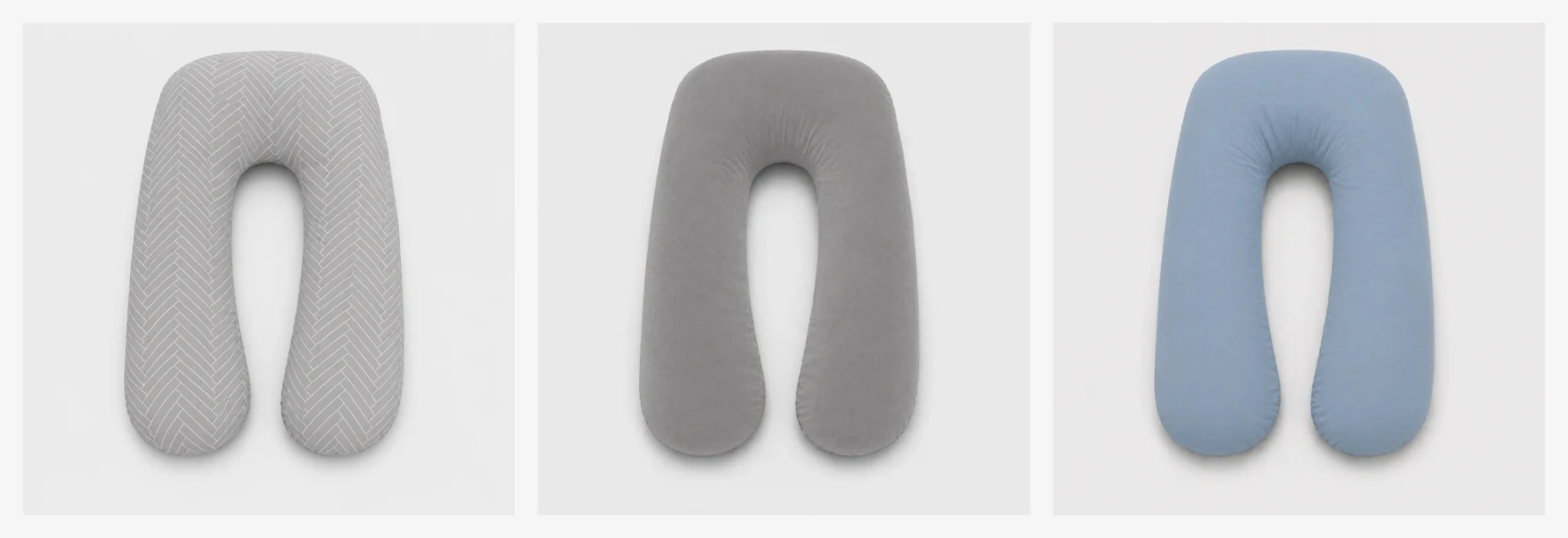 The pregnancy pillow’s three colours side by side on a light background: herringbone grey, plain grey and blue