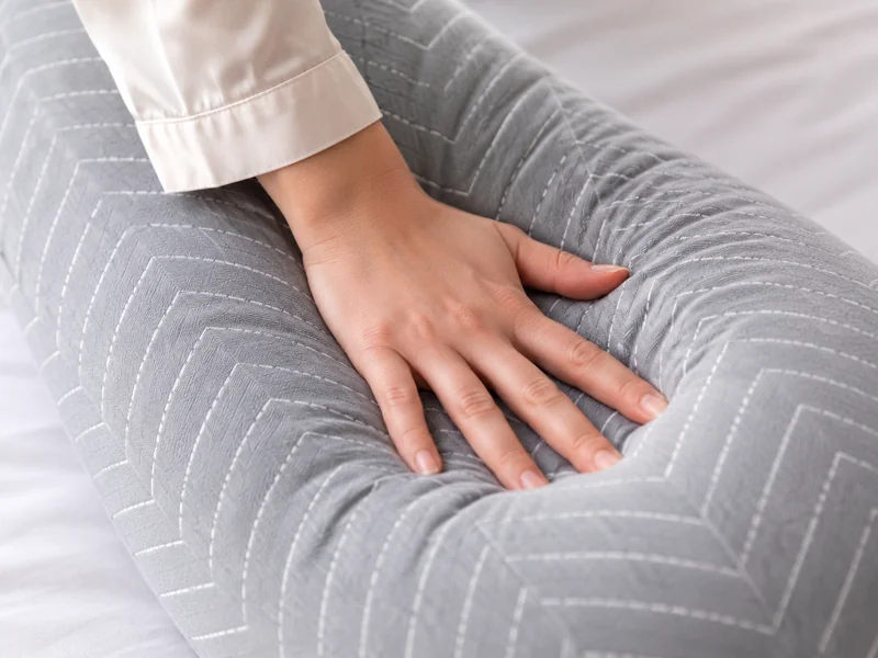 A hand pressing flat on the pillow’s arm to judge its firmness